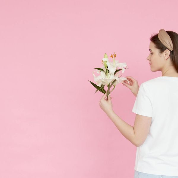 Person stretching gracefully, silhouetted against a soft pink light.